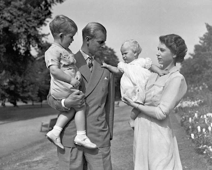 Princess-Anne-in-the-arms-of-Princess-Elizabeth-with-the-Duke-of-Edinburgh-holding-Prince-Charles-in-the-grounds-of
