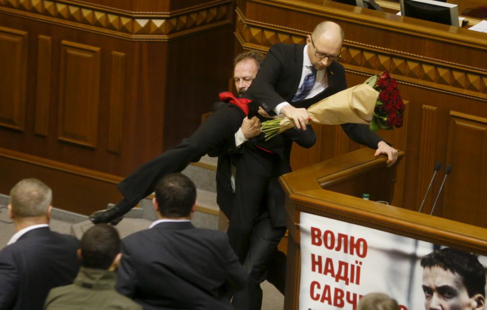 Rada deputy Oleg Barna removes Prime Minister Arseny Yatseniuk from the tribune, after presenting him a bouquet of roses, during the parliament session in Kiev, Ukraine, December 11, 2015. REUTERS/Valentyn Ogirenko