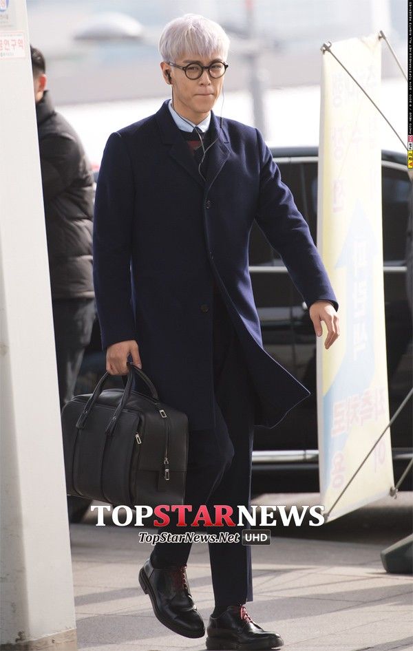 T.O.P chỉnh chu với bộ vest tối màu, đeo kính gọng tròn, xách túi như một quý ông trẻ. Trang phục của rapper cá tính không nhàm chán nhờ mái tóc tím nhạt nổi bật.