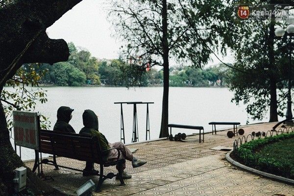 Hai người mặc kín bưng ngồi trò chuyện bên bờ Hồ.