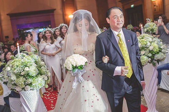 Cô dâu Trà My phủ voan che mặt và khoác tay bố tiến vào làm lễ.