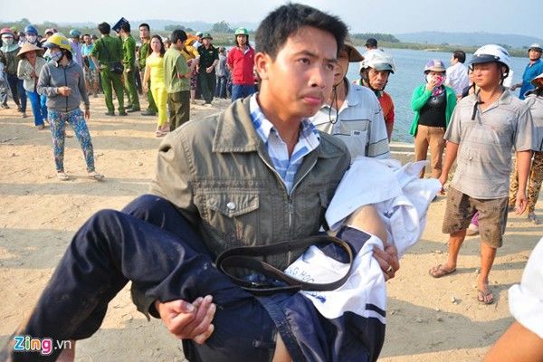 Một người đưa thi thể học sinh lên bờ.