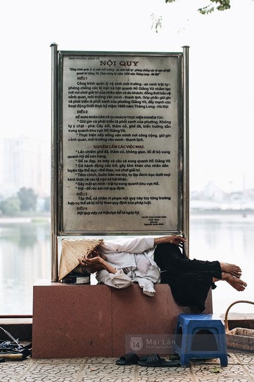 Lúc vãn khách, bà Nhẫn nằm nghỉ ngay dưới biển báo nội quy ở ven hồ Giảng Võ.