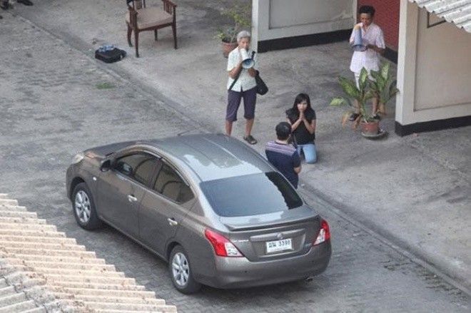 Nữ sinh viên quỳ trước tiến sĩ Wanchai Danaitamonut khi ông ta bước ra khỏi xe và dí súng vào đầu ở thành phố Bangkok, Thái Lan hôm 19/5. Ảnh: Bangkok Post. 