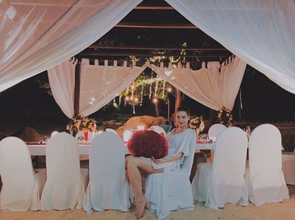 Nữ ca sĩ hạnh phúc ôm bó hoa giống hệt bó hoa trong bức ảnh trên bãi biển.