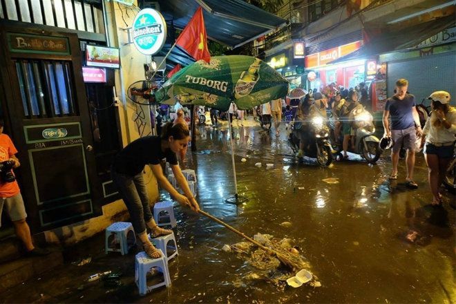 Một chủ quán đang cố khai thông dòng chảy trước đống rác dồn ứ lại.