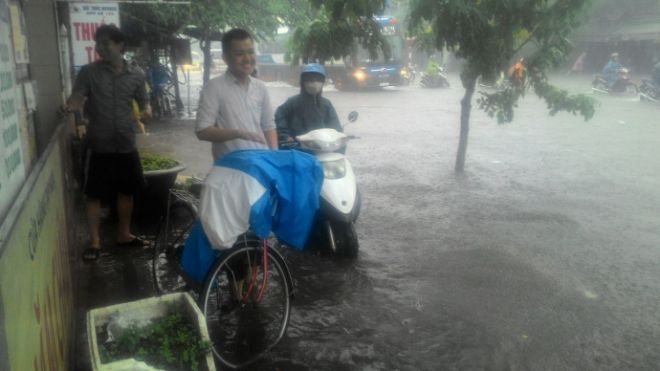 Nước ngập quá sâu kèm mưa lớn khiến nhiều người chỉ còn biết tránh vào lề đường.