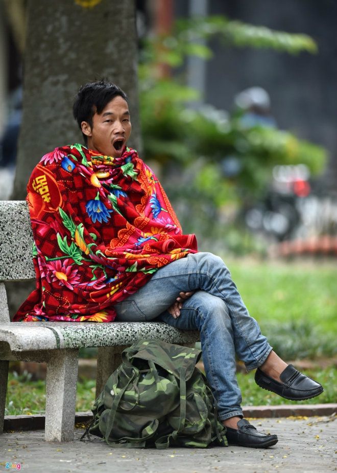 Một người đàn ông quấn chiếc chăn quanh mình ngồi ghế đá vườn hoa Quán Sứ. Thời tiết thay đổi khiến anh không kịp thích nghi, ngáp ngủ liên tục.