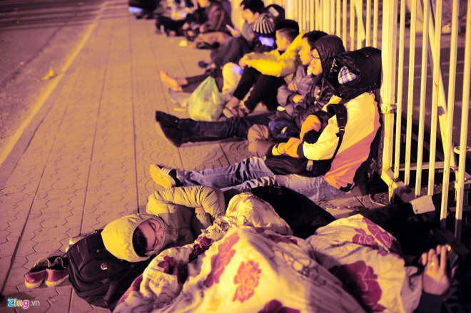 Những người không mang chăn chiếu ngồi dựa hàng rào ngủ.