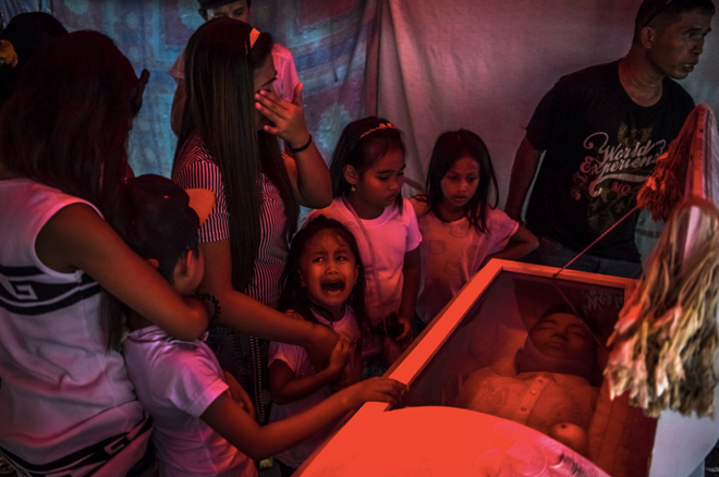 Cô bé Jimji, 6 tuổi, khóc bên quan tài của người cha Jimboy Bolasa, 25 tuổi, khi thi thể của anh chuẩn bị được đưa đi chôn cất. Ảnh: NYT.