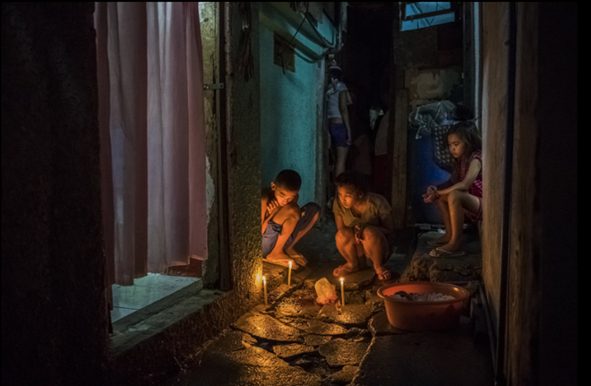 Roel Scott, 13 tuổi, thắp nến để tưởng nhớ người chú Joselito Jumaquio, 52 tuổi, ở nơi ông bị bắn chết. Ảnh: NYT.