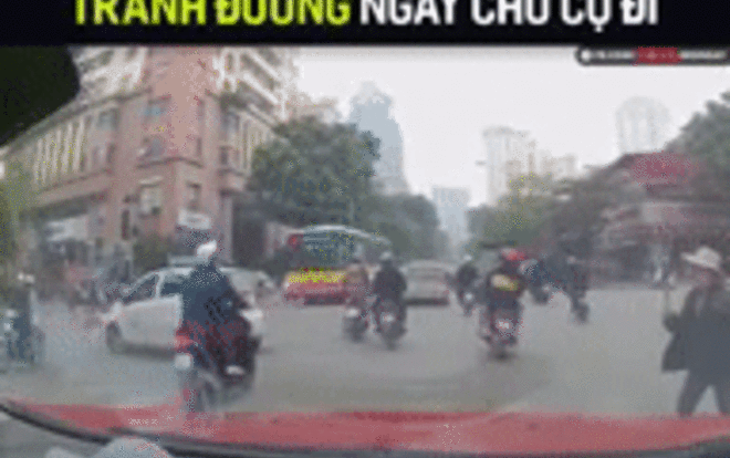 Cụ bà lăm lăm cây gậy dài trên tay vụt mạnh vào đầu xe ô tô đang lưu thông để sang đường Ảnh 2