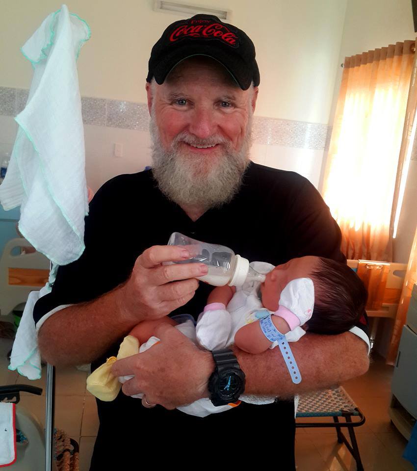 Ông Paul đang ẵm trên tay đứa trẻ thứ 14 được sinh ra trong dự án Jenny hỗ trợ các bà mẹ đơn thân.