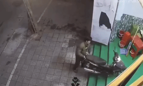 Người chồng loay hoay dắt xe máy vào nhà một mình. Ảnh cắt từ clip