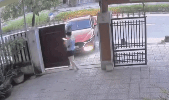 Cô vừa cầm điện thoại trên tay vừa kéo cổng.  Ảnh cắt từ clip. (Nguồn: Kiều Trang Nguyễn)