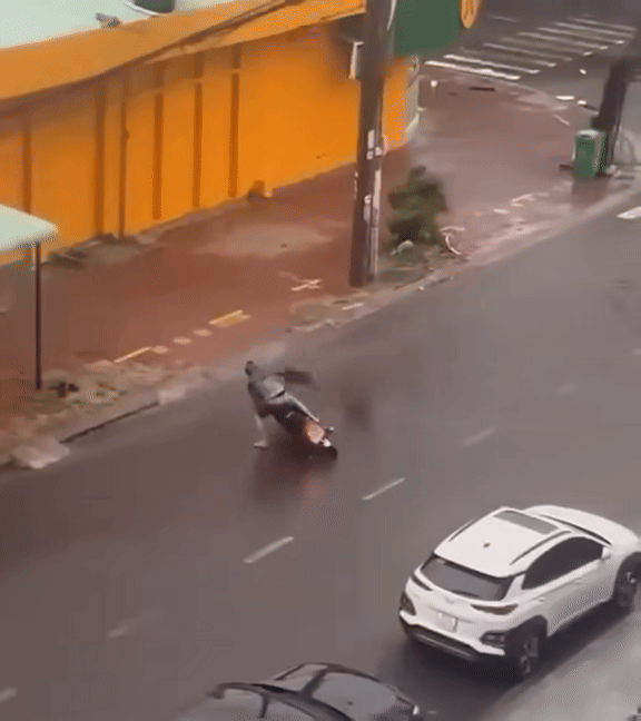 Gió bão quật mạnh khiến thanh niên không thể di chuyển, đành bỏ xe máy giữa đường. Ảnh cắt từ clip/Hóng Đường Phố