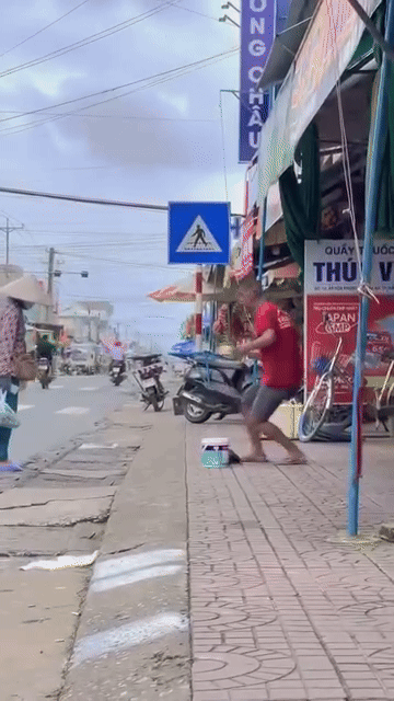 Đứng trên vỉa hè, người đàn ông vẫn câu được rất nhiều cá. Ảnh cắt từ clip