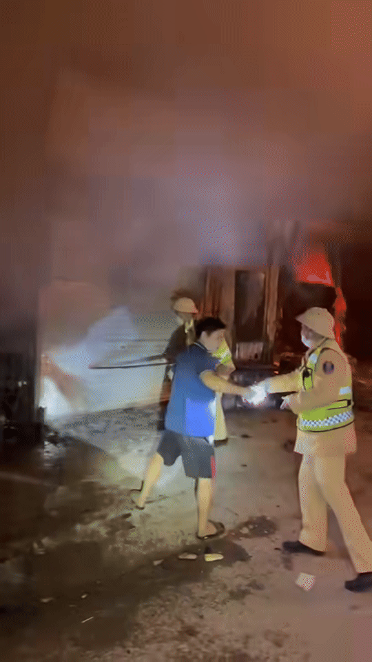 Lực lượng chức năng phá cửa cứu những người mắc kẹt bên trong ngôi nhà đang cháy. Ảnh cắt từ clip