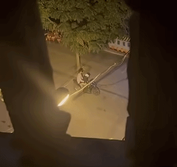 Cặp đôi nam nữ bị bắt gặp có hành động thân mật ở dưới lề đường, khiến dân mạng rôm rả bàn luận. Ảnh cắt từ clip/Nguồn: Page Hóng Đường Phố