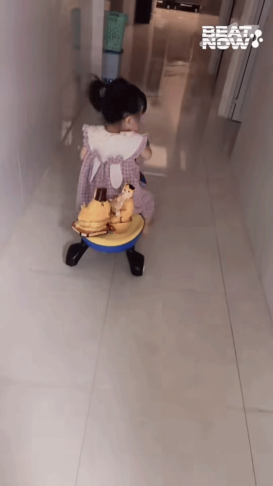 Vừa thay đồ trở ra, người mẹ hú hồn khi thấy con gái đang chở ông Thần Tài - Thổ Địa trên xe chòi chân. Ảnh cắt từ clip