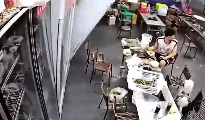 Thanh niên vừa rời bàn ăn để giúp đỡ người khác thì chiếc tủ bất ngờ đổ ập xuống. Ảnh cắt từ clip