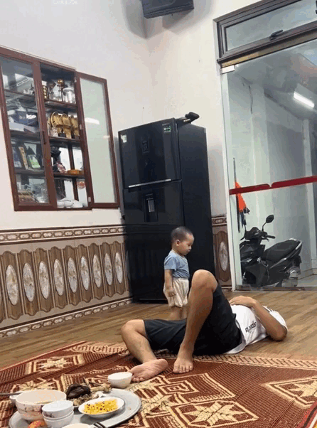Thấy bố nằm xuống chiếu dù mâm cơm đã được dọn ra, cậu bé lập tức chạy đến tủ lạnh...Nguồn: Bảo Nam