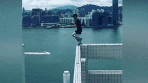 Chàng trai ung dung đi trên mép tường các toà cao ốc