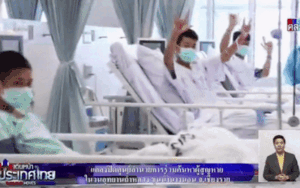 Các cầu thủ đội bóng Thái Lan mỉm cười, giơ tay chào khi ở trong phòng cách ly