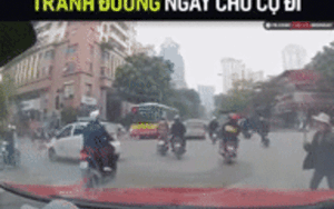 Cụ bà lăm lăm cây gậy dài trên tay vụt mạnh vào đầu xe ô tô đang lưu thông để sang đường