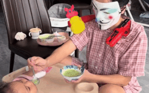 Mẹ đeo mặt nạ hoá trang thành chú hề, con vừa ăn dặm vừa ngơ ngác không hiểu chuyện gì xảy ra