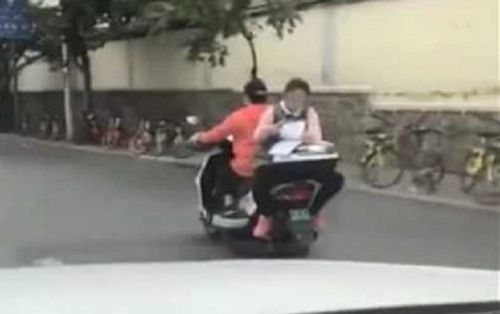 Choáng váng trước cảnh bé gái tranh thủ làm bài khi ngồi sau xe máy đang chạy