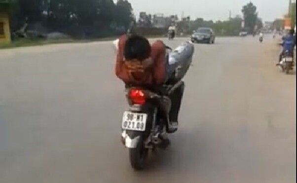 Lái xe máy bằng chân, tay điện thoại 'Alo mẹ, con đang đi chậm lắm'