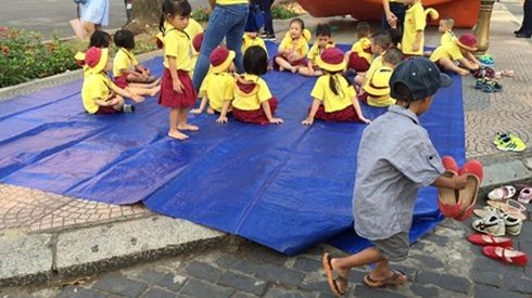 Em bé theo mẹ nhặt rác hồn nhiên xếp dép cho các bạn dã ngoại