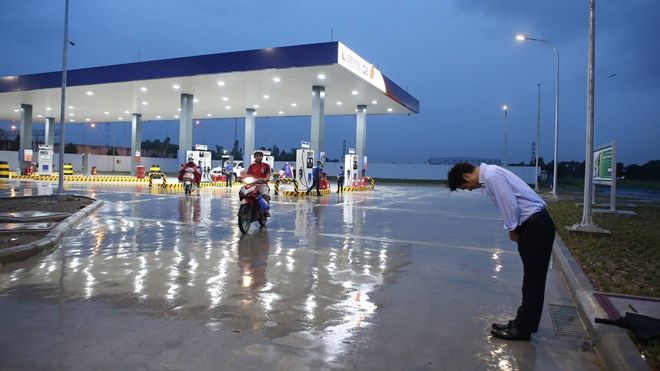 Giám đốc cây xăng Nhật cúi chào và Thượng đế trên băng rôn