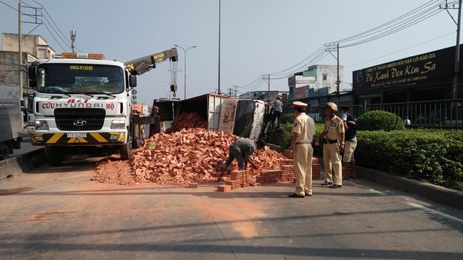 Xe tải chở gạch lật ngang, tài xế cùng phụ xe mắc kẹt kêu cứu trong cabin