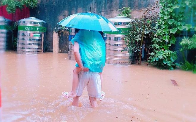 Xúc động hình ảnh bố cặm cụi cõng con gái lội qua con đường ngập nước để đến điểm thi