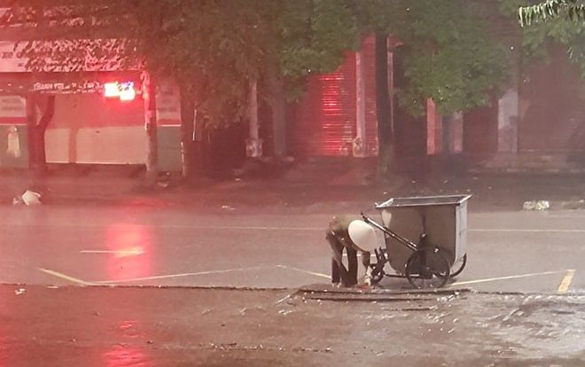 Xúc động khoảnh khắc cô lao công cặm cụi dọn rác cho khỏi tắc cống dưới trời mưa lớn trong đêm