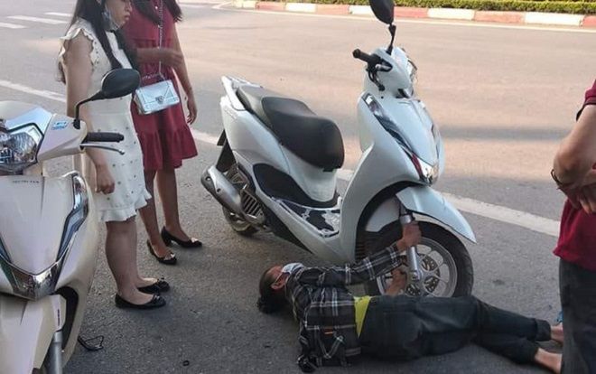 Bức ảnh người phụ nữ lớn tuổi nằm dưới đường, hai tay ôm lấy bánh xe máy gây xôn xao