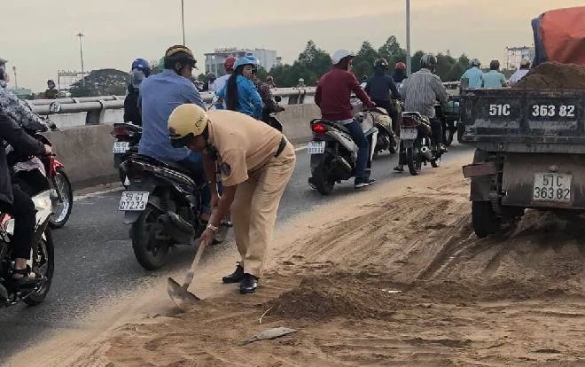 Ấm lòng hình ảnh CSGT tay cầm xẻng xúc đất vương vãi trên cầu vượt ở Sài Gòn