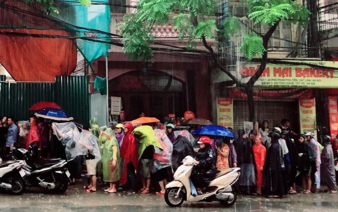 Mưa lớn, cửa hàng phát áo mưa cho khách đang chờ mua bánh trung thu