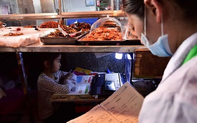 Cay khóe mắt với hình ảnh bé gái ngồi học dưới gầm sạp hàng của bố mẹ ngoài chợ