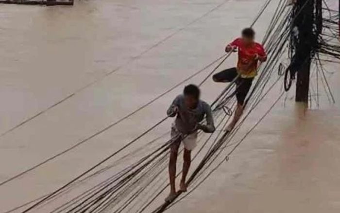 Người dân liều mình đi trên dây điện để thoát thân giữa dòng lũ khiến mạng xã hội xôn xao