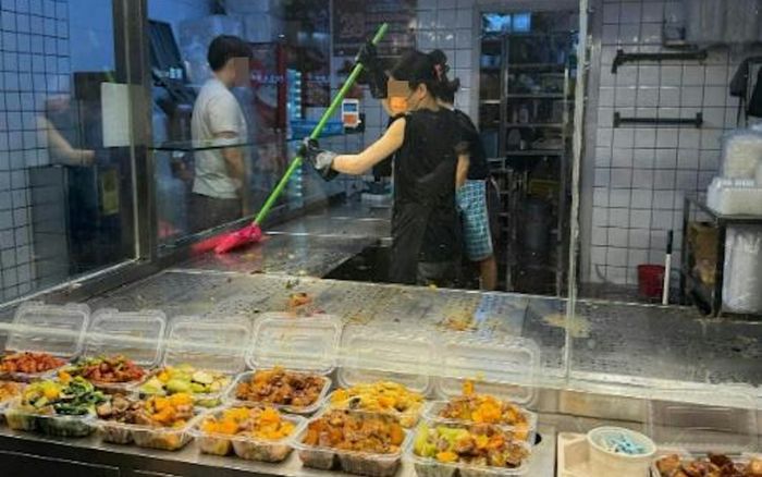 Xôn xao hình ảnh 2 nhân viên nhà hàng dùng chổi để quét khay đựng thức ăn