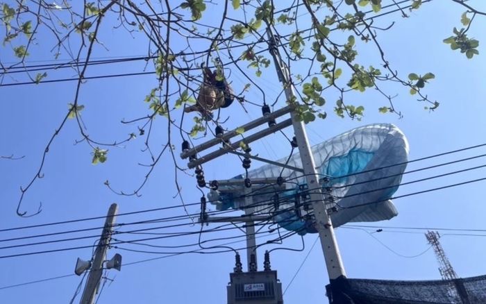 Du khách nước ngoài mắc kẹt trên cột điện cao thế khi chơi dù lượn, cảnh tượng khiến người dân xôn xao