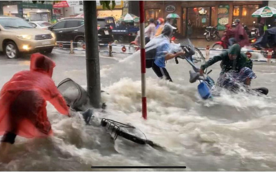 Bất chấp dòng nước chảy xiết do mưa lớn để đạp xe về nhà, nhóm học sinh ngã nhào xuống đường khiến nhiều người thót tim