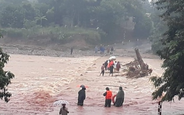 Lực lượng biên phòng cùng người dân đưa sản phụ qua cầu tràn ngập nước lũ đi sinh