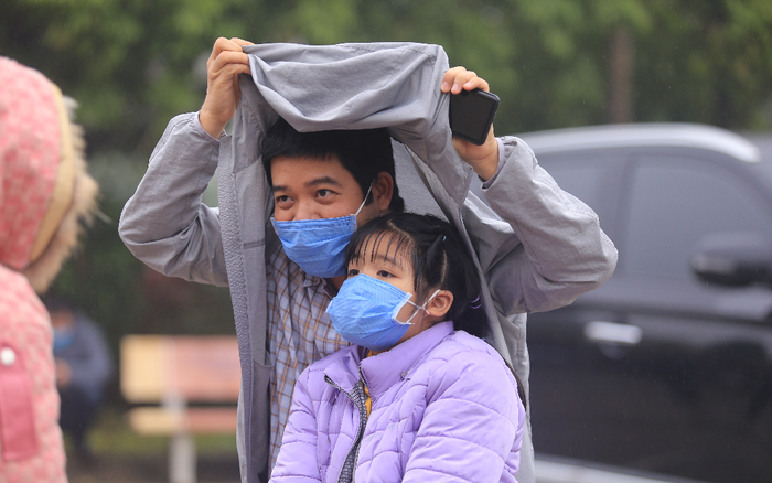 Phụ huynh trường tiểu học nơi có ca nhiễm đội mưa đưa con đi xét nghiệm COVID-19