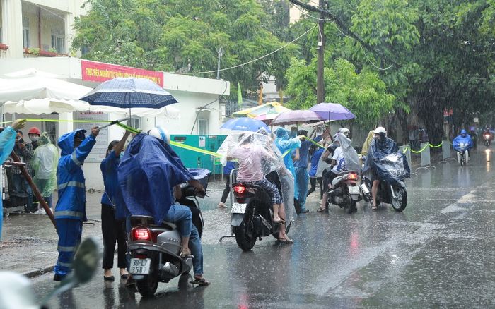 Hà Nội: Phụ huynh đội mưa đưa con đi thi, phải về lấy quần áo gửi đến phòng thi cho con thay