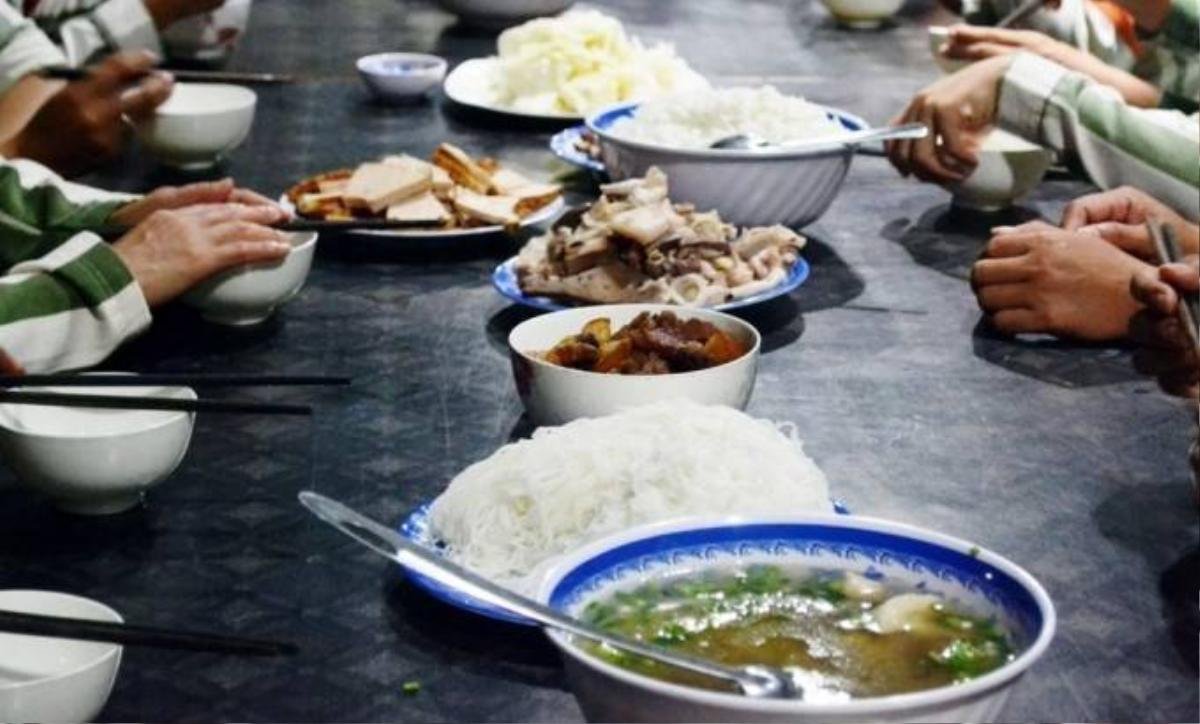 Trên bàn ăn gồm các món rau xanh, thịt kho, chân giò hầm, chả lụa...