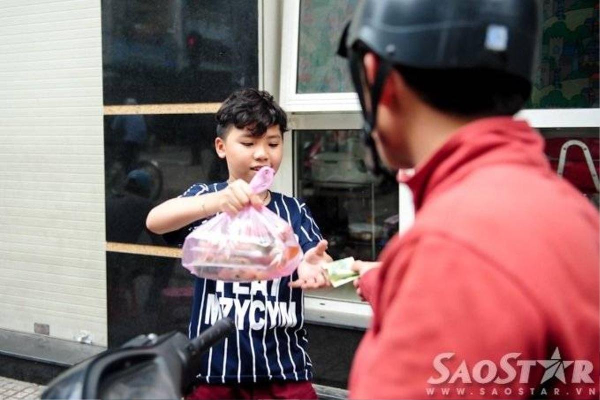 Cậu nhóc vui vẻ bán bánh cho khách trong khi mẹ mình tất bật chiết nước chấm vào túi ni lông nhằm kịp giờ giao số hàng đặt. 